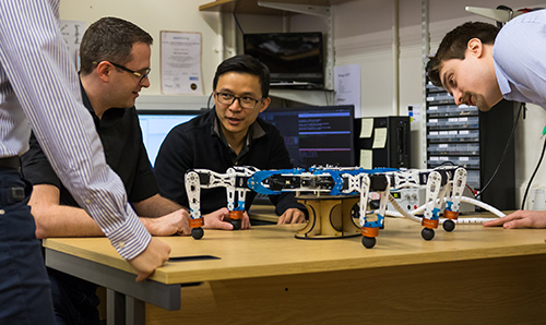 Researchers in discussion around a robotic spider